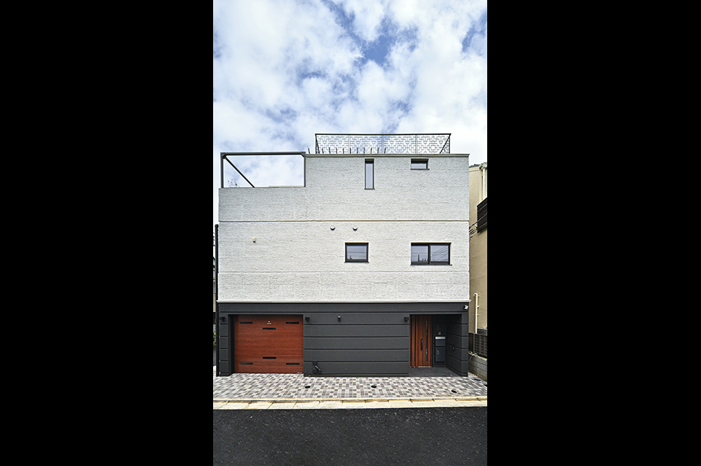 シンプルで美しい箱形の3階建て。1階の黒い外壁に木のドアがよく似合います。